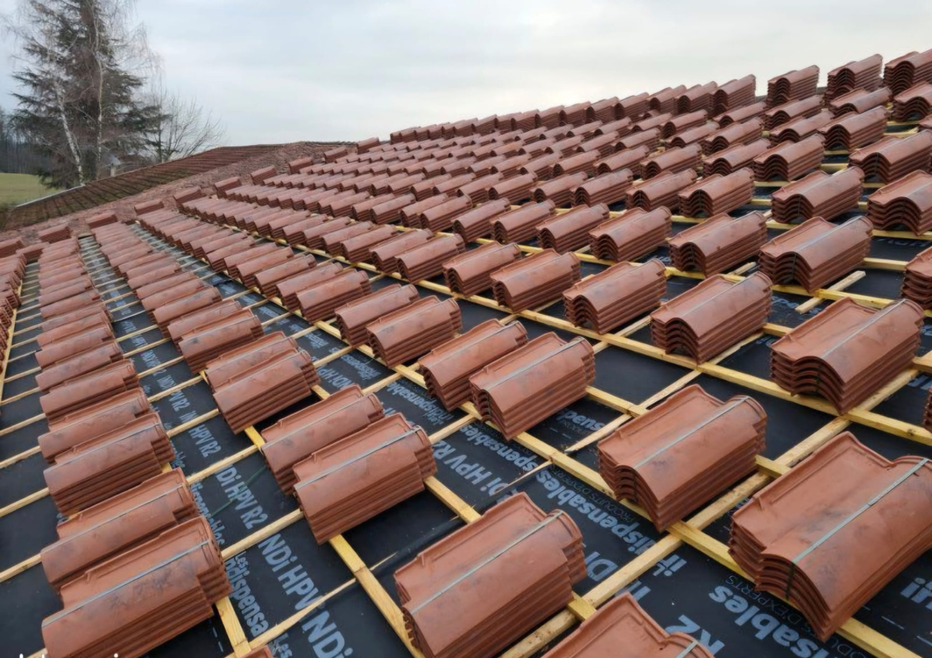 Chantier de couverture avec tuiles en attente sur liteaux