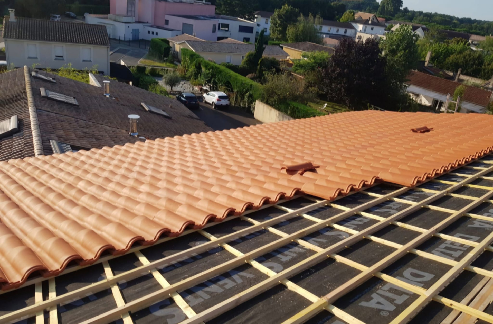 Pose de tuiles neuves orange sur écran sous-toiture dans la vallée de l'Isère